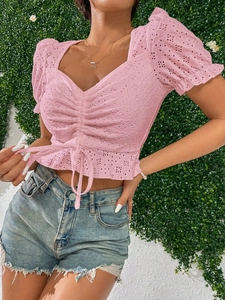 Détail du haut en maille rose à col en V avec broderie ajourée et cordon de serrage