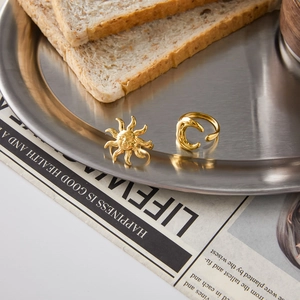 Detailed shot of celestial sun and moon rings on a vintage tray with warm lifestyle aesthetic