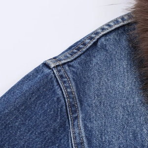 Detail of blue denim jacket showing shoulder stitching and brown faux fur collar texture