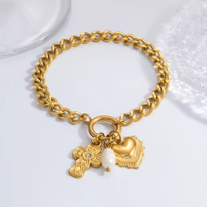 Detail of golden chunky chain bracelet with cross, heart pendant and white baroque pearl