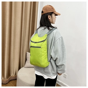 Side view of lightweight neon green waterproof folding backpack worn by a model