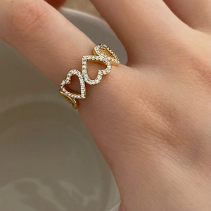 Elegant 18K gold-plated open heart ring with micro-set zircons on a beige background