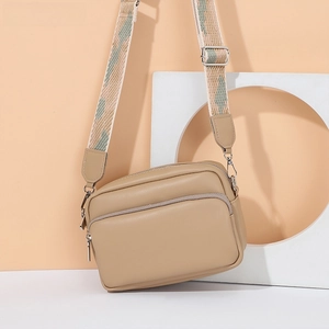 Dettaglio borsa fotografica beige con tracolla jacquard geometrica e finiture metalliche argentate