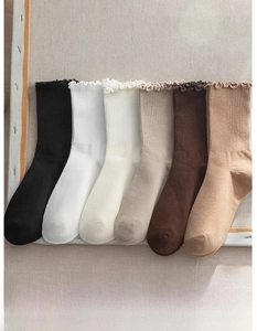 Detail view of women's ribbed socks with ruffle cuffs in earthy tones on canvas