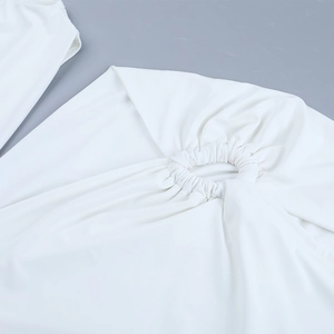 Detail shot of the white dress featuring elegant ruched fabric and circular cutout design