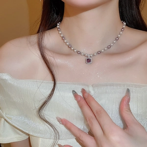 Macro view of vintage pearl necklace with square purple zircon pendant on model