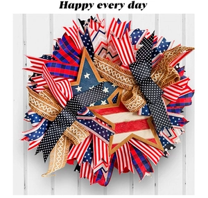 Close-up of patriotic wreath with red, white and blue ribbons and wooden stars on wood