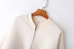 Detailed close-up of cream zip-up bomber jacket collar with ribbing and XS size tag