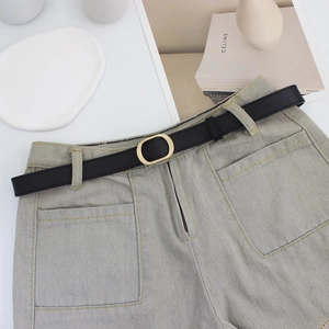 Damen schmaler schwarzer Ledergürtel mit goldener ovaler Schnalle auf Denim-Shorts