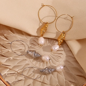 Close-up of gold and silver seashell earrings with pearls on elegant satin background