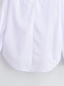 Detail view of the curved shirt-tail hem and back seam on a white long sleeve cotton top
