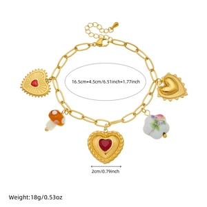 Gold-plated charm bracelet with heart, mushroom, and floral ceramic pendants on white background