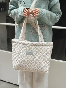 Detailed macro view of the quilted texture and delicate blue floral pattern on the tote bag