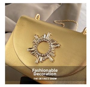Macro detail of golden evening bag showing the starburst rhinestone buckle and fine texture