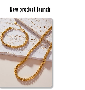 Detailed shot of golden twisted weave necklace and bracelet set on a textured stone plate