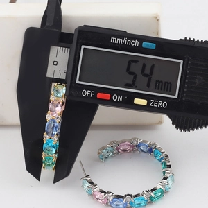 Macro view of measuring colorful zircon C-shape earring width with digital caliper