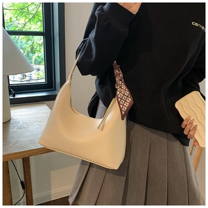 Detail of cream white underarm bag with a decorative geometric print silk scarf handle