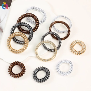 Macro shot of metallic spiral hair ties in gold and silver on a white decorative plate