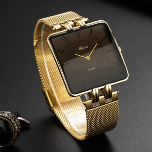 Detailed close-up of golden stainless steel mesh strap and square watch case on dark background