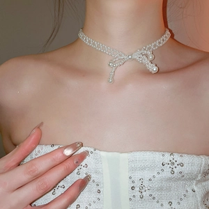 Vue détaillée du collier de perles élégant avec pendentif nœud porté par un mannequin