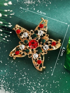 Detailed view of a gold Christmas star brooch with red and green crystals on pine