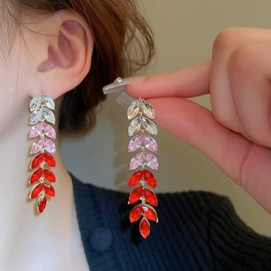 Luxurious tassel leaf earrings with gradient red rhinestones worn by a model