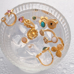 Close-up of gold-plated rings with stars and turquoise gemstones in an ice bowl