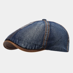 Detail of washed denim flat cap showing dark blue fabric and brown leather brim trim