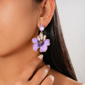 Macro detail of purple enamel flower earring with sparkling crystal stud on model