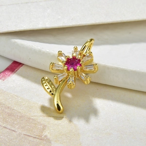 Detail of golden sunflower pendant with pink gemstone and clear cubic zirconia stones
