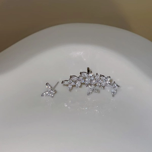 Macro detail of asymmetric butterfly stud and petal ear cuff set with bright cubic zirconia