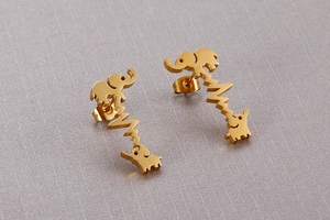 Macro detail of gold stainless steel elephant heartbeat earrings on grey textured surface