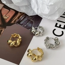Details von polierten goldenen und silbernen gedrehten Creolen mit klobiger Metallstruktur