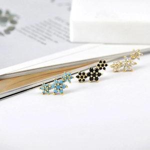 Macro shot of three snowflake stud earrings with colorful zircon stones on a magazine