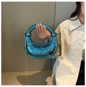 Close-up of blue crescent acrylic bag with quilted texture and gold chain strap detail