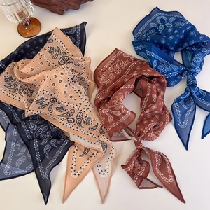 Detailed flat lay of paisley print scarf necklaces in black, beige, rust and navy blue colors