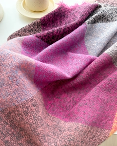 Close-up of pink and grey plaid cashmere-feel scarf showing soft wool texture and tassels
