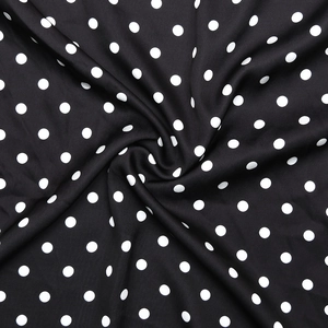 Vue détaillée du tissu noir à pois blancs montrant la texture et le drapé fluide