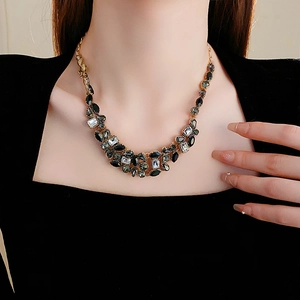 Gros plan d'un collier goutte vintage avec cristaux noirs et dorés sur un modèle