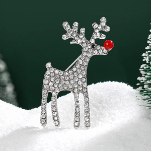 Broche de renne de Noël avec strass blancs scintillants et nez rouge sur la neige