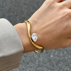 Elegante bracciale rigido dorato a onde con zircone a goccia sul polso