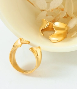 Macro detail of wave-shaped gold rings displayed on elegant ceramic with white petals