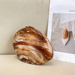 Close-up of stylish acrylic clutch bag featuring brown and white marble stone texture