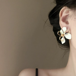 Close-up of elegant double-layered white floral earrings with golden hollow detailing