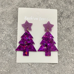 Macro view of purple glitter acrylic Christmas tree earrings with star stud detail