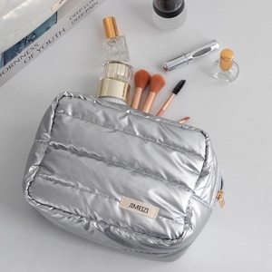 Silver puffy cosmetic bag with quilted texture and gold zipper for travel organization
