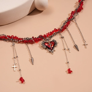 Detail of gothic heart necklace with red crushed stones and silver cross charms