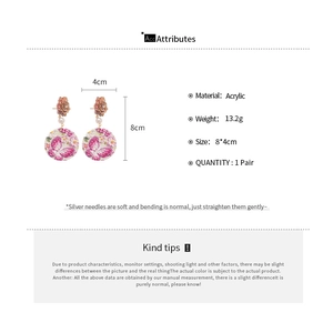 Detail view of acrylic floral drop earrings with butterfly patterns and silver needles
