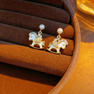 Detail of 14k gold plated rocking horse earrings with pearls and zircon in a box