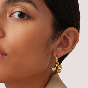 Boucles d'oreilles cerises en acier inoxydable plaqué or 18 carats portées par un modèle